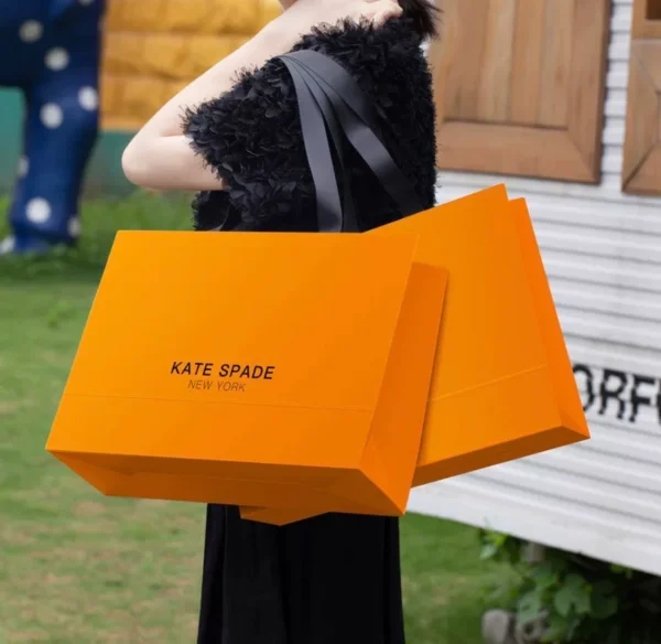 A woman carrying two paper bags with Kate Spade printed on them