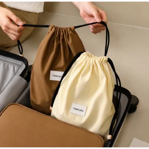 Brown and cream high-density Oxford drawstring bags with black cords and small printed labels, packed into a suitcase.